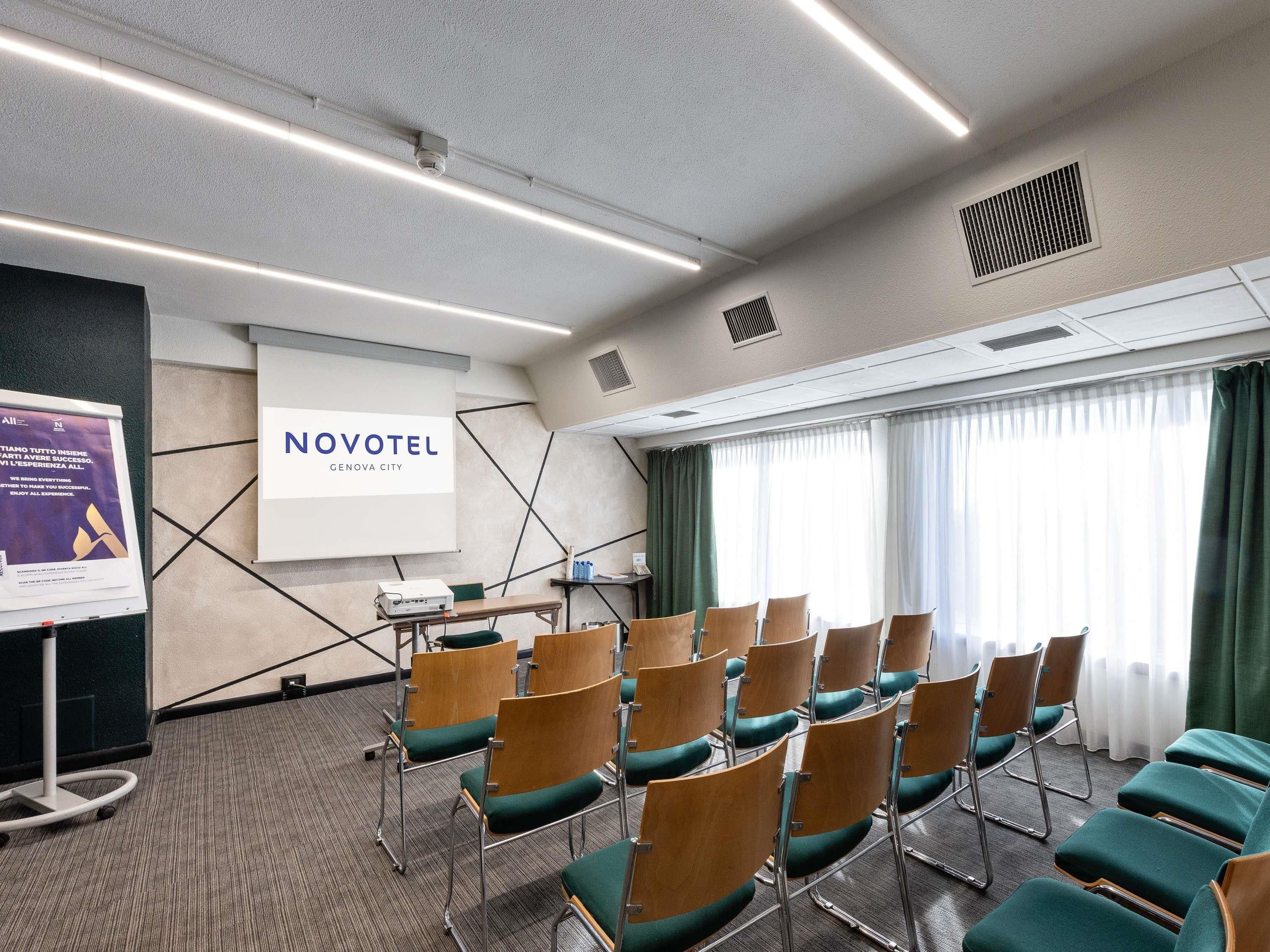 A conference room with rows of chairs, a projector screen, and a presentation board.