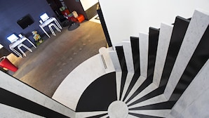 Un interno moderno con una scala a chiocciola, una zona reception e un’area salotto con una poltrona rossa.
