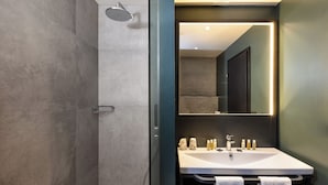 Un bagno moderno con cabina doccia in vetro, un lavabo bianco e uno specchio grande.