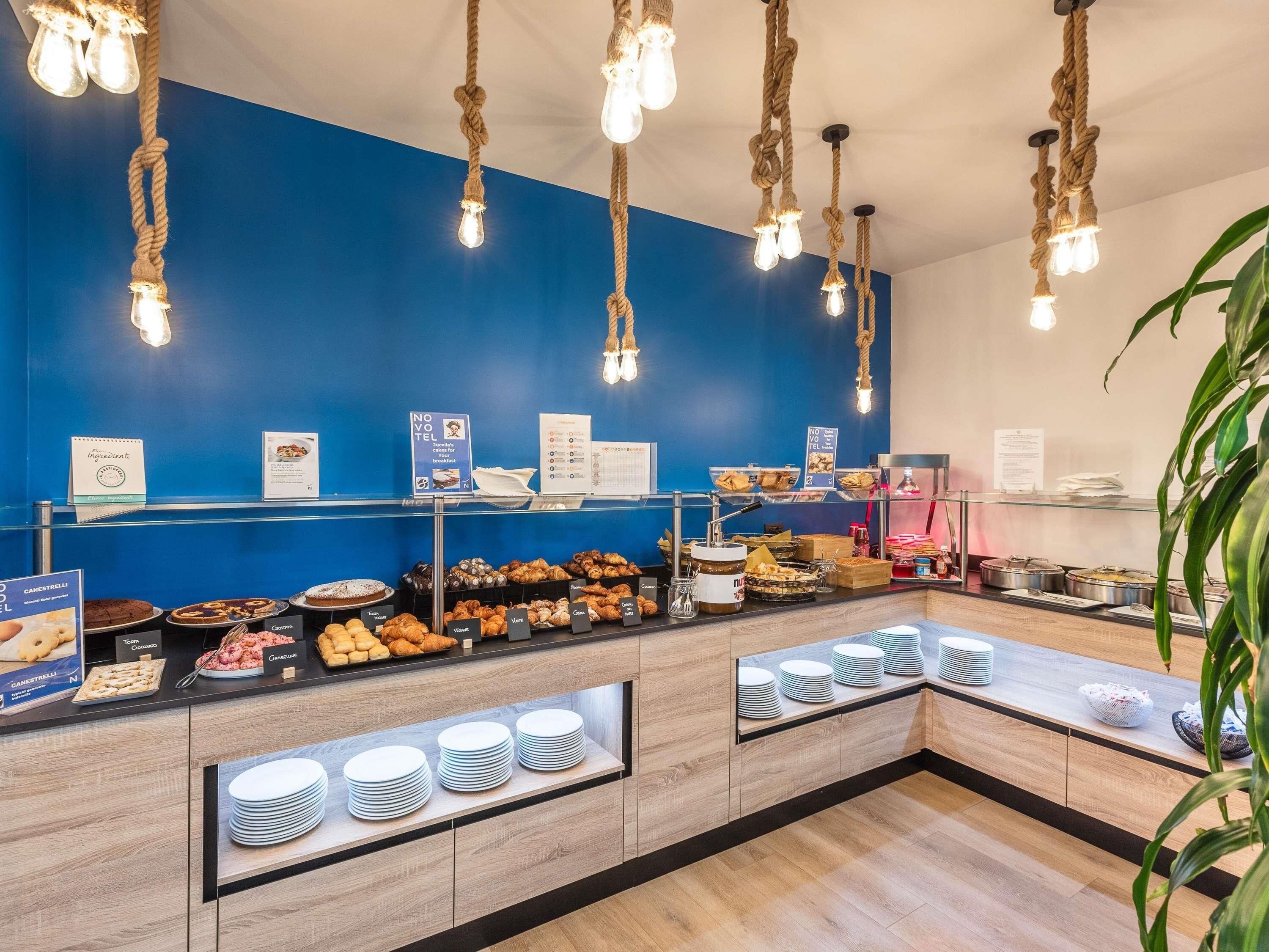 A buffet area with various food items, a blue wall, and hanging light fixtures.