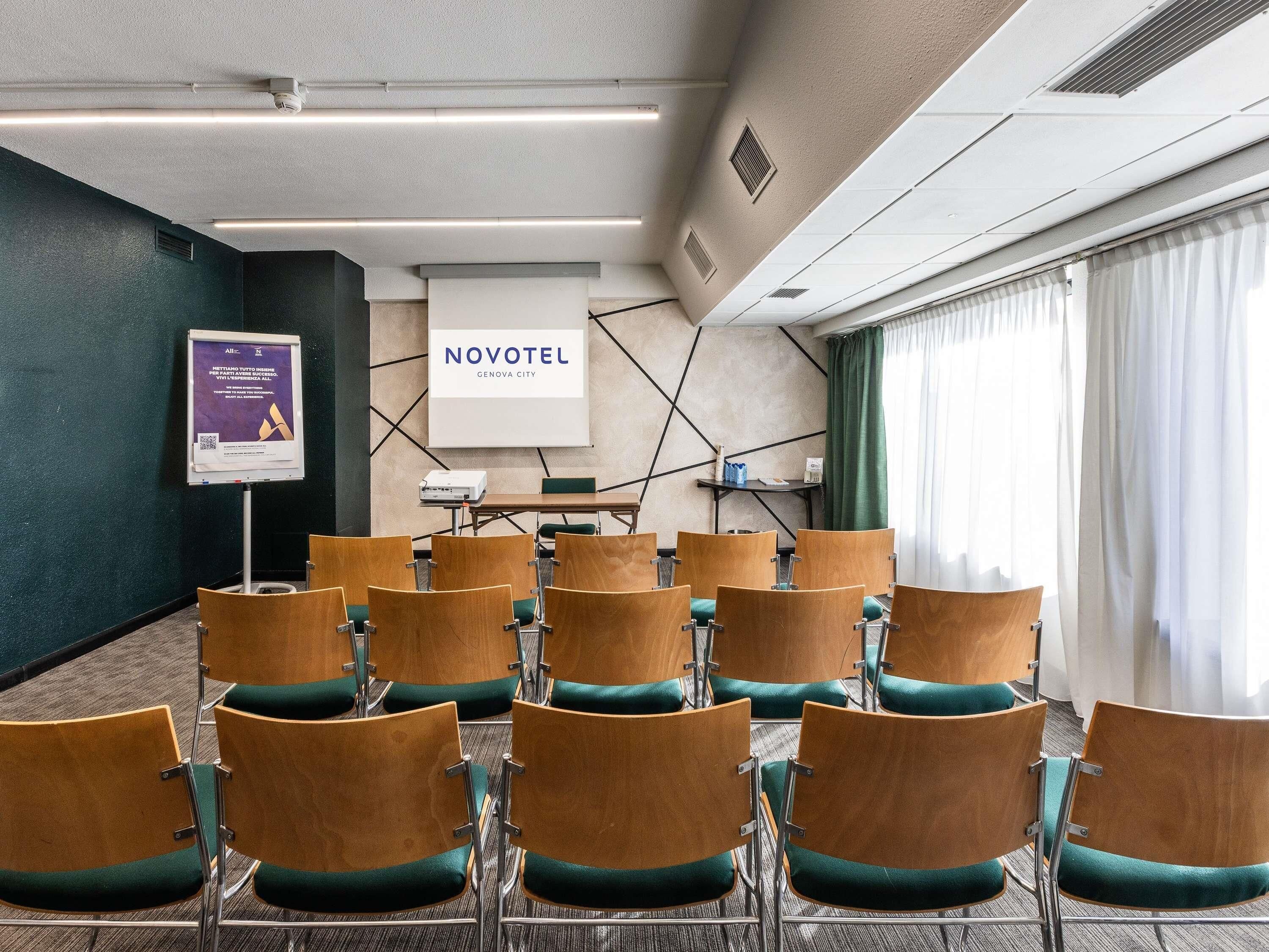 A conference room with rows of chairs, a projector screen, and a presentation board.