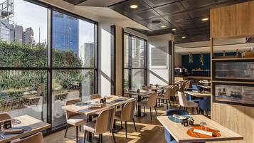 Un'area pranzo moderna con ampie finestre, diversi tavoli e sedie.