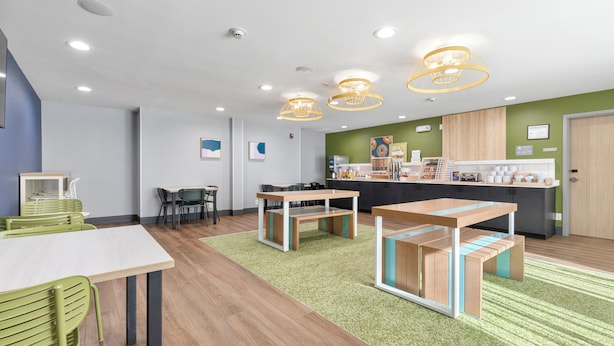 Une cuisine moderne avec des plans de travail en bois, un îlot central et des chaises vertes.