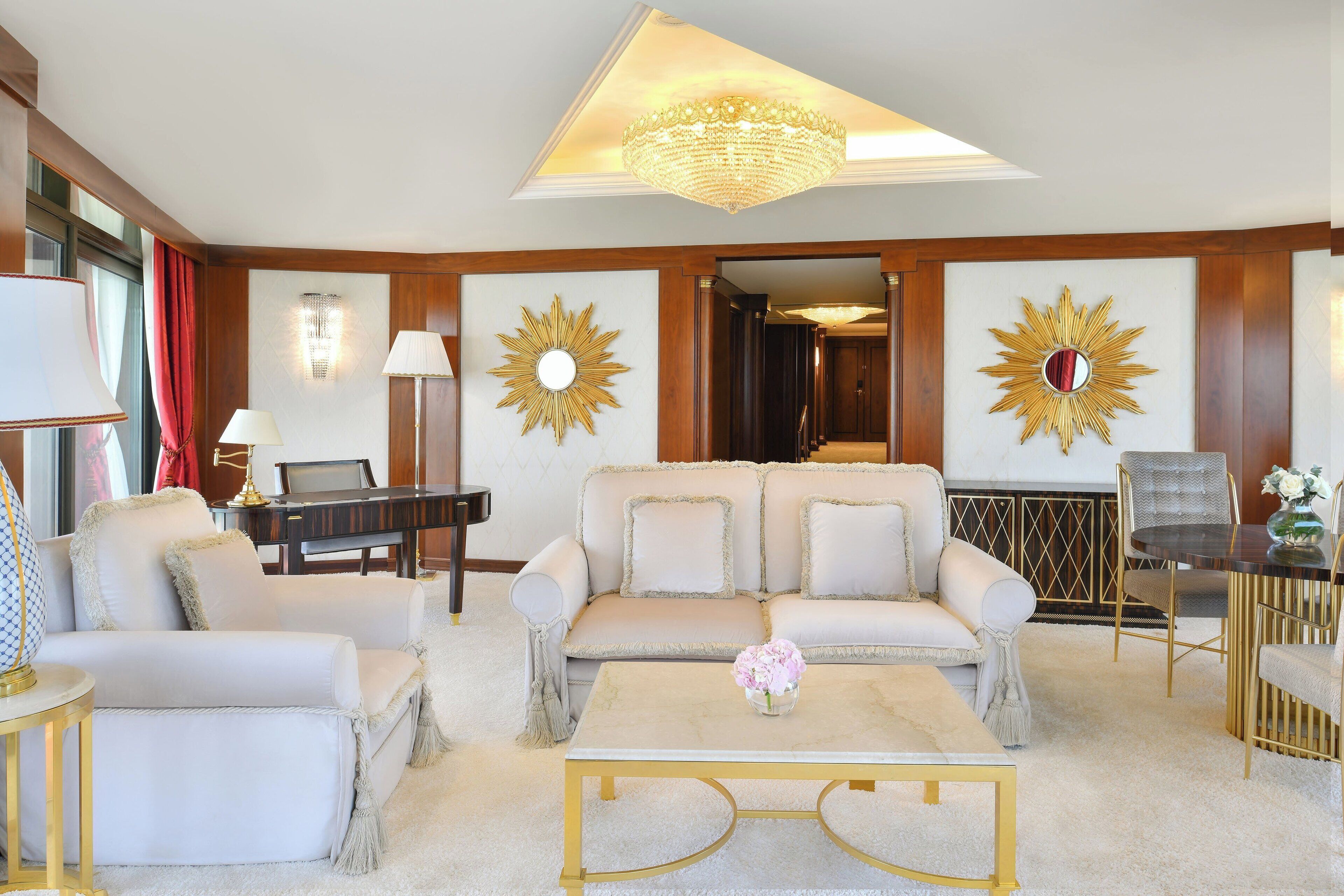 A spacious living room with a sofa, armchairs, a coffee table, and a piano.