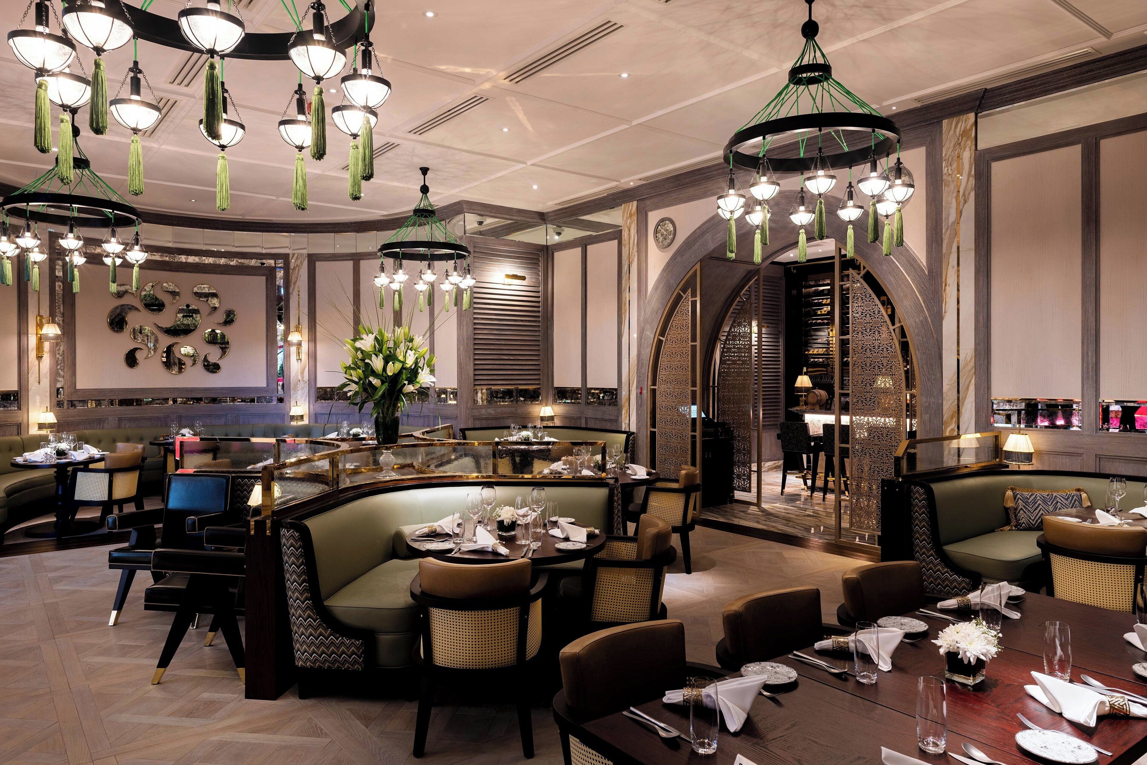 A spacious hotel lobby with multiple seating areas, including a central round table and several sofas.