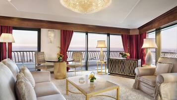 A spacious living room with a large chandelier, comfortable seating, and a view of the ocean.