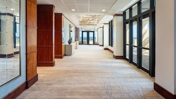 A hotel corridor with wooden paneling, large windows, and a patterned carpet.