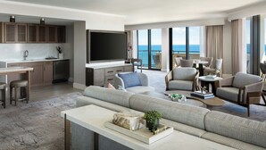 A modern living room with a large sofa, a coffee table, and a flat-screen TV. There is a balcony with a view of the ocean. - Fort Lauderdale Marriott Harbor Beach Resort & Spa (Fort Lauderdale)