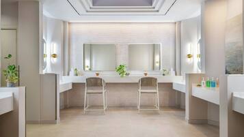 A modern bathroom with two sinks, mirrors, and chairs.