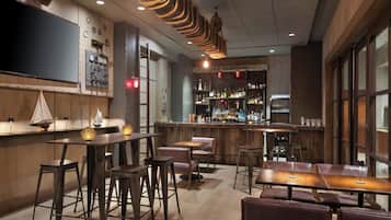 A bar area with wooden tables, stools, and a bar counter with bottles and glasses.
