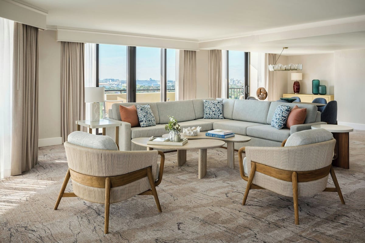Een ruime woonkamer met een grote hoekbank, twee fauteuils, een salontafel en een eethoek met een tafel en stoelen.