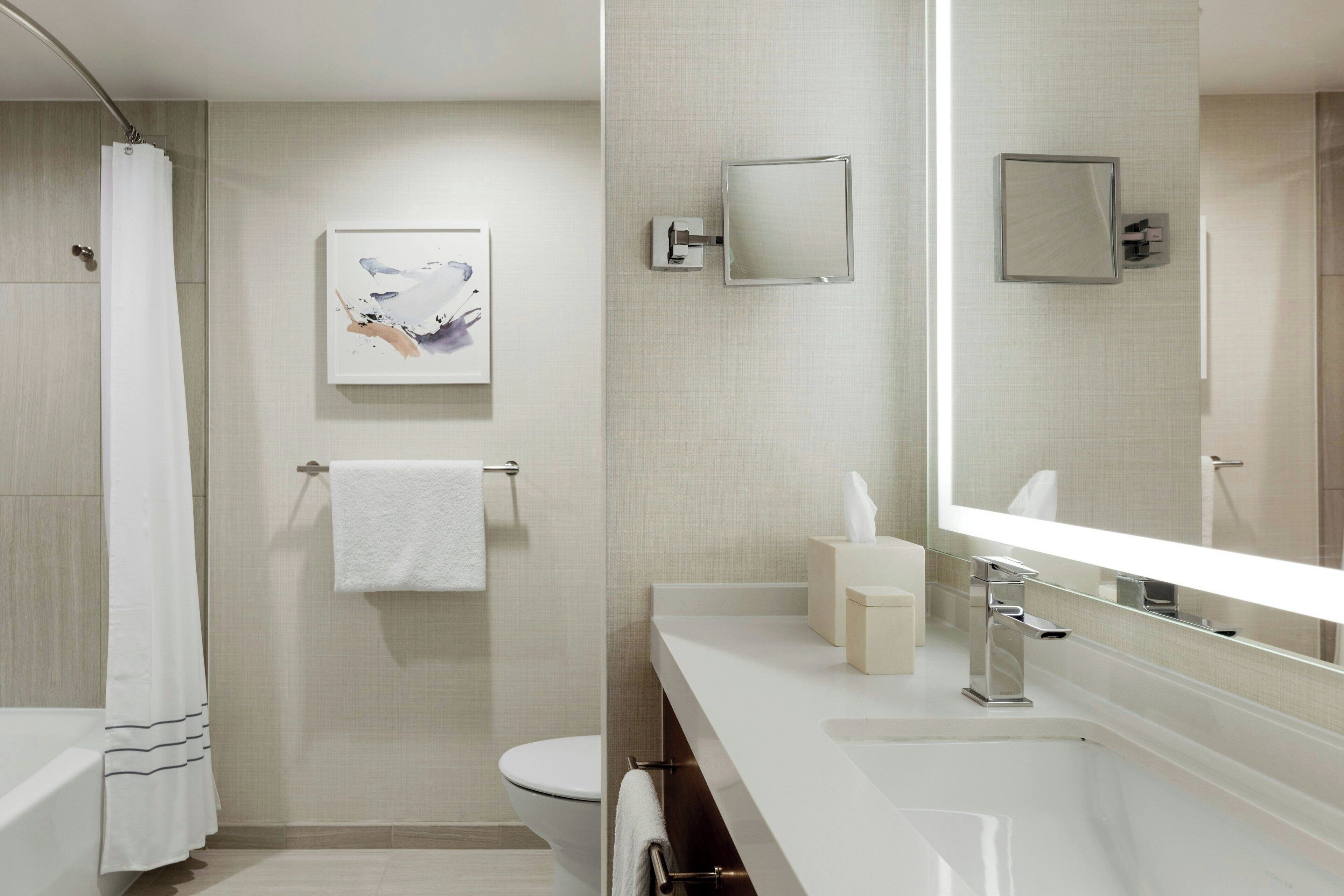 A modern bathroom with a bathtub, toilet, and a large mirror.