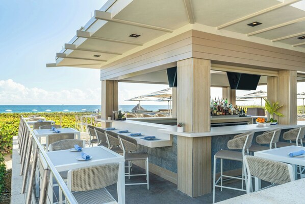 An outdoor bar area with seating and a view of the ocean.