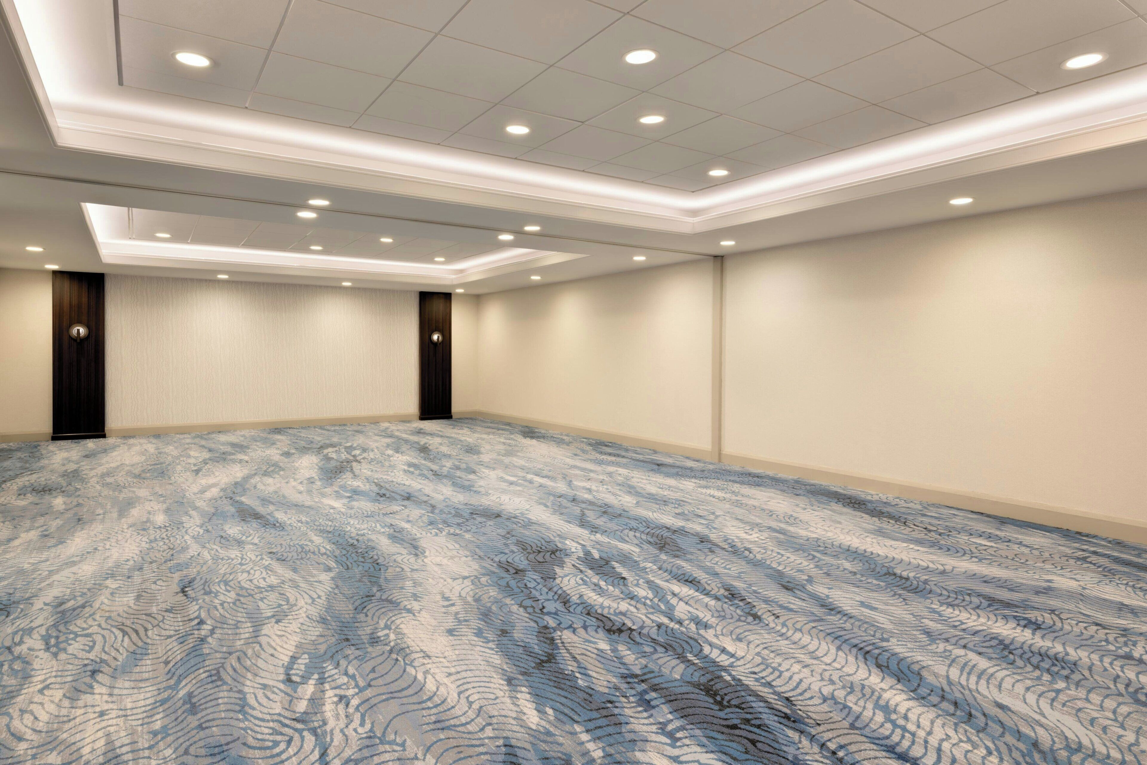 A conference room with a patterned carpet, recessed ceiling lights, and plain walls.
