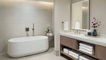A modern bathroom with a freestanding bathtub, a large mirror, and a vanity with shelves for towels.