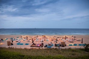 A beachside event with tables and chairs arranged for guests, overlooking the ocean.