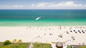 A beach with clear turquoise water, a sandy shore, and a few umbrellas and lounge chairs.