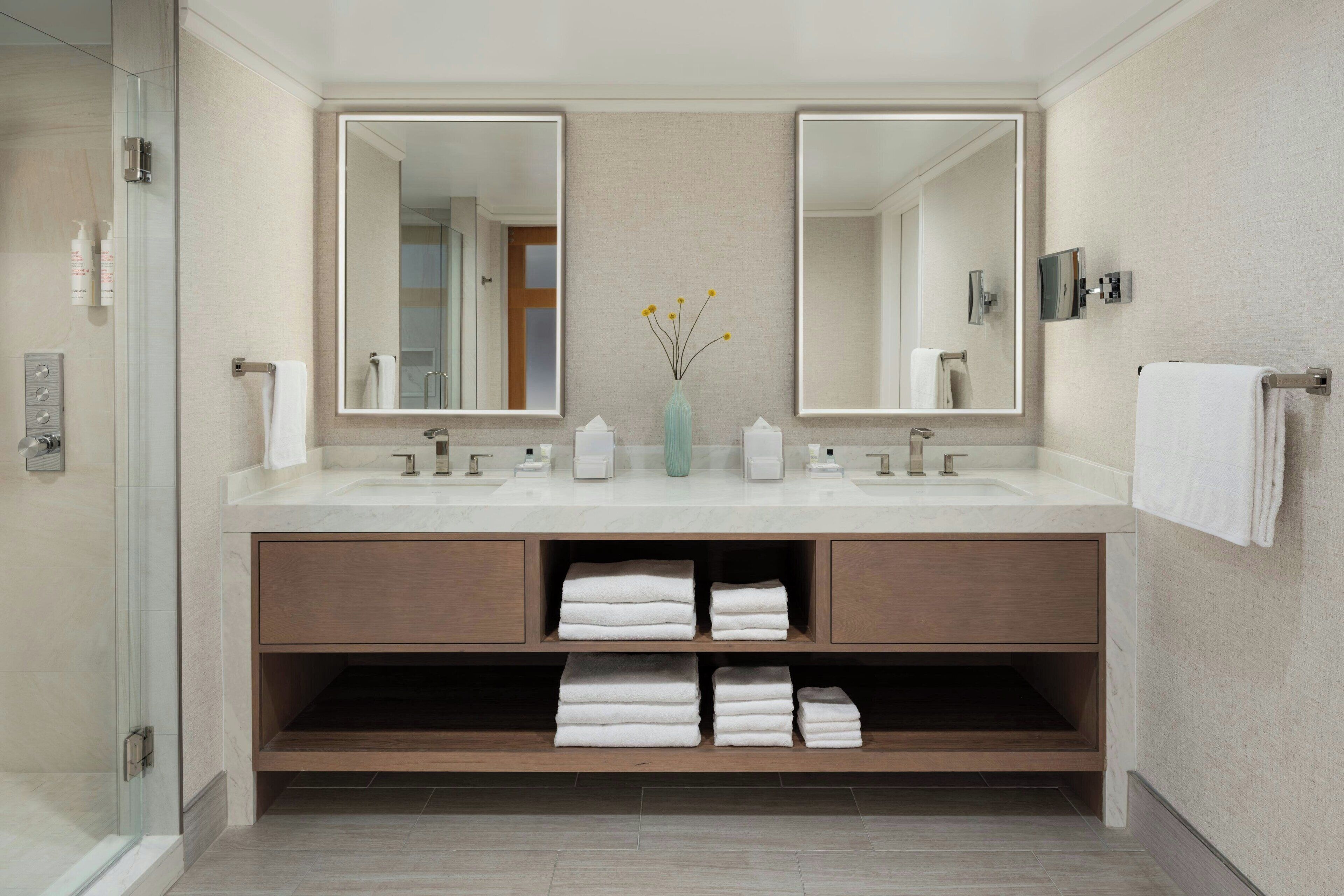 Un baño moderno con dos lavamanos, un espejo grande y una cabina de ducha de vidrio.