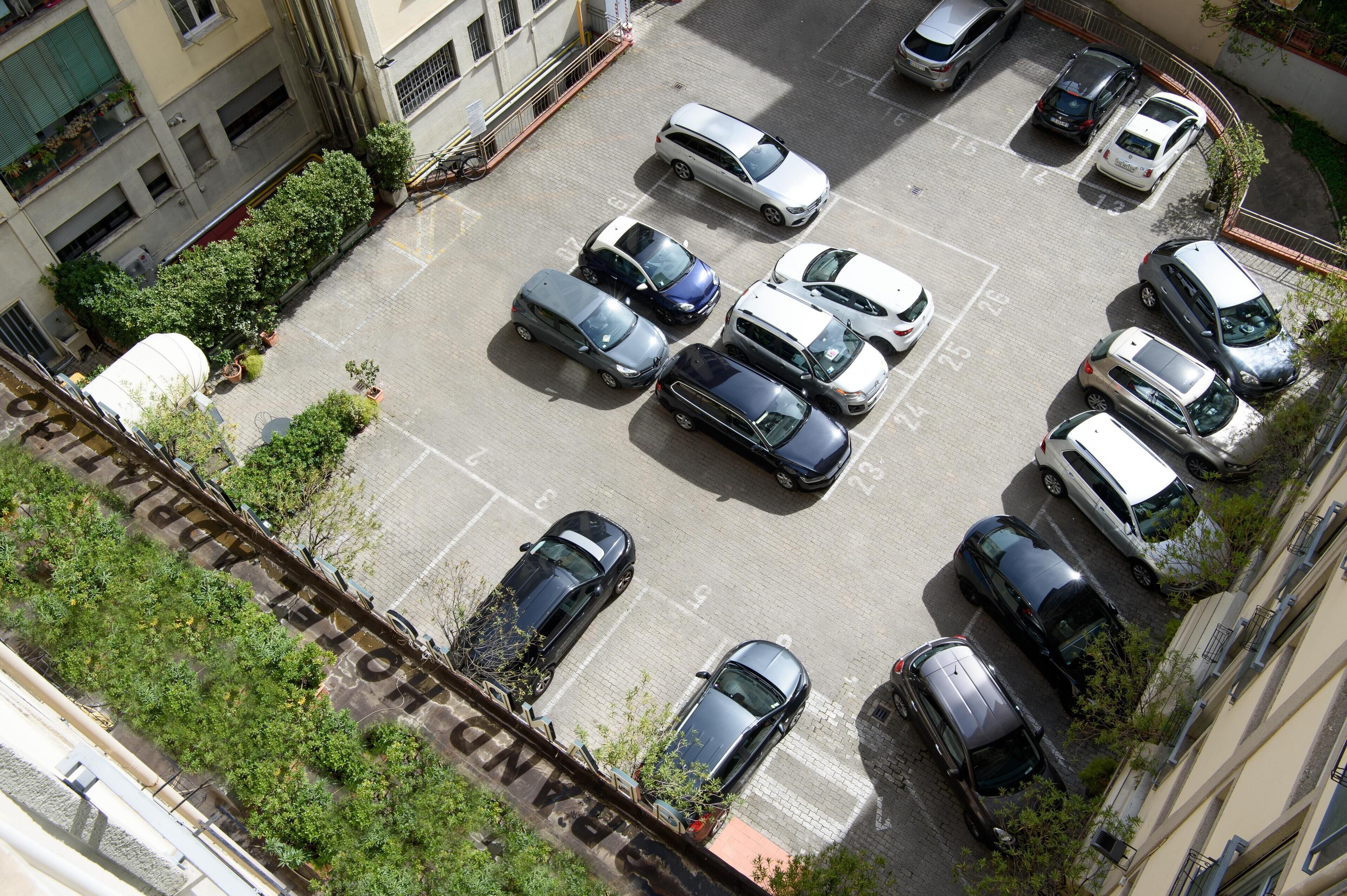 An aerial view of a parking lot with multiple cars and a few trees.