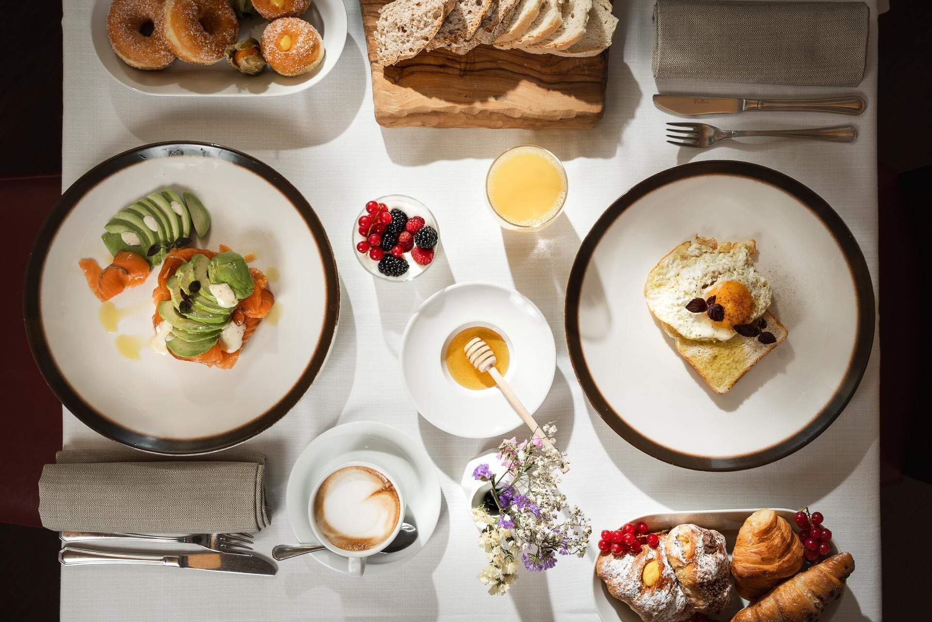 Une table mise pour le petit-déjeuner, avec des assiettes remplies de nourriture, un verre de jus, une tasse de café et une serviette.