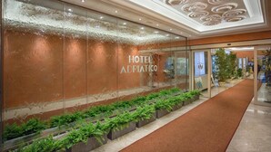 A hotel entrance with a glass facade, a red carpet, and a ceiling with circular patterns. - Grand Hotel Adriatico (Florence)