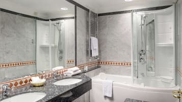 Ein Badezimmer mit zwei Waschbecken, einer Badewanne, einer Dusche und einem großen Spiegel.
