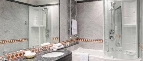 Un baño con dos lavamanos, una bañera, una ducha y un espejo grande.