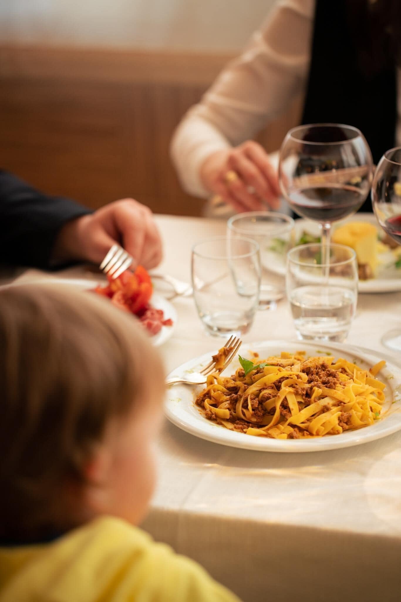 A dining table with plates of food, glasses, and cutlery.