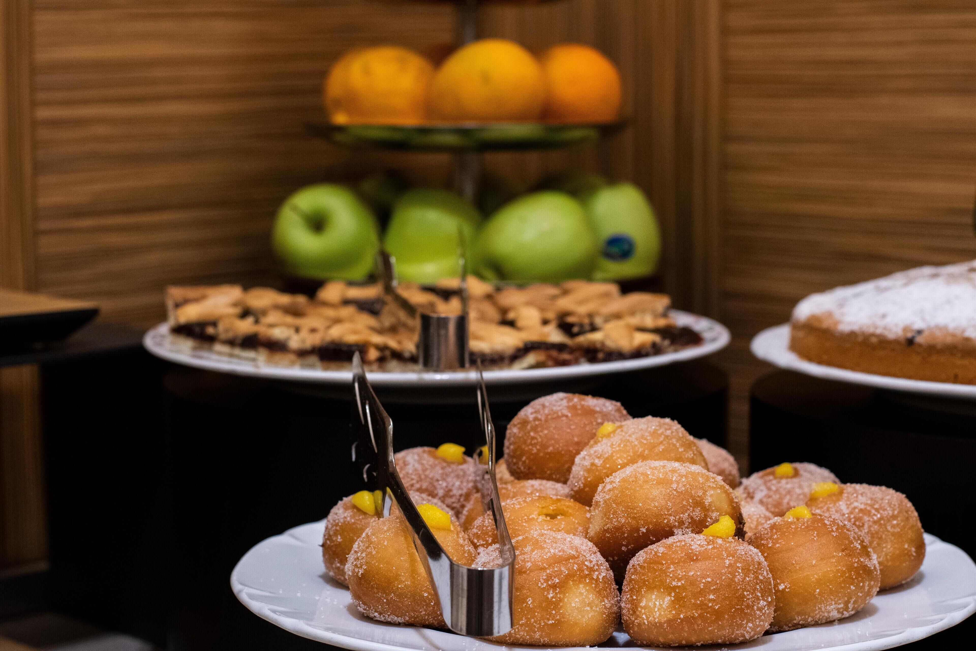 Un buffet proposant une variété de desserts, notamment des beignets, une présentation de fruits et un gâteau.