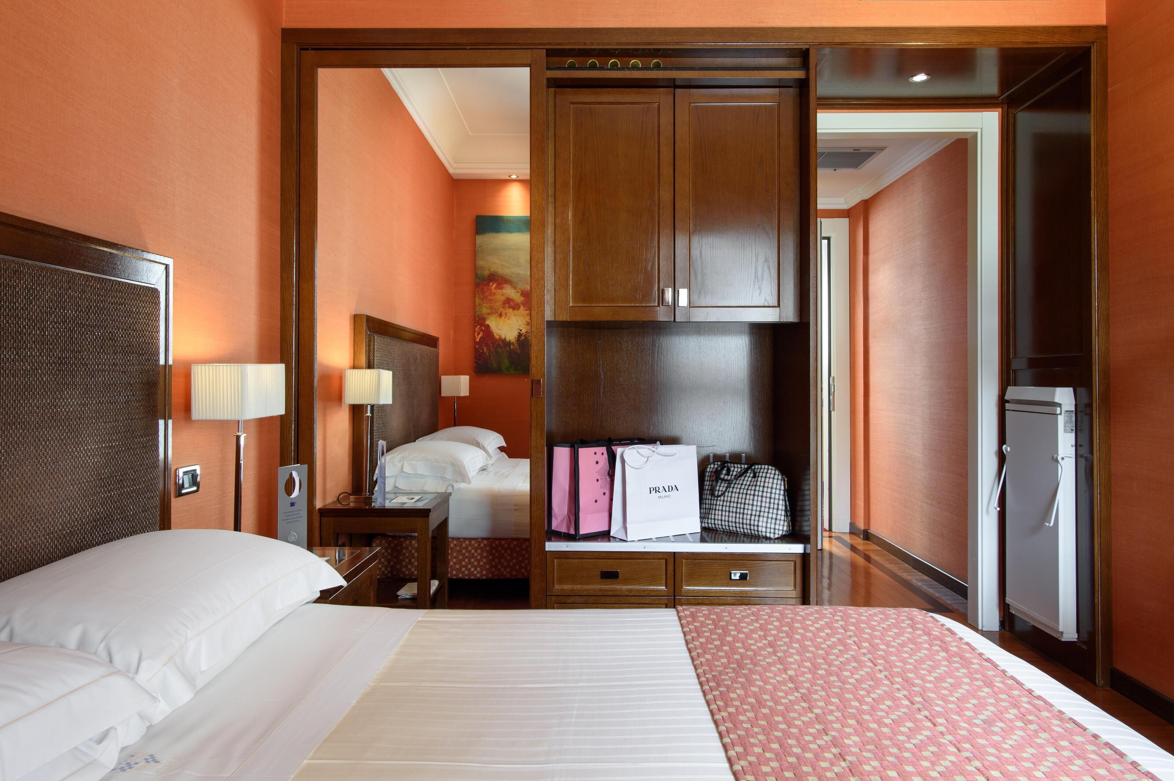 A hotel room with a bed, bedside table, lamp, and a wardrobe.