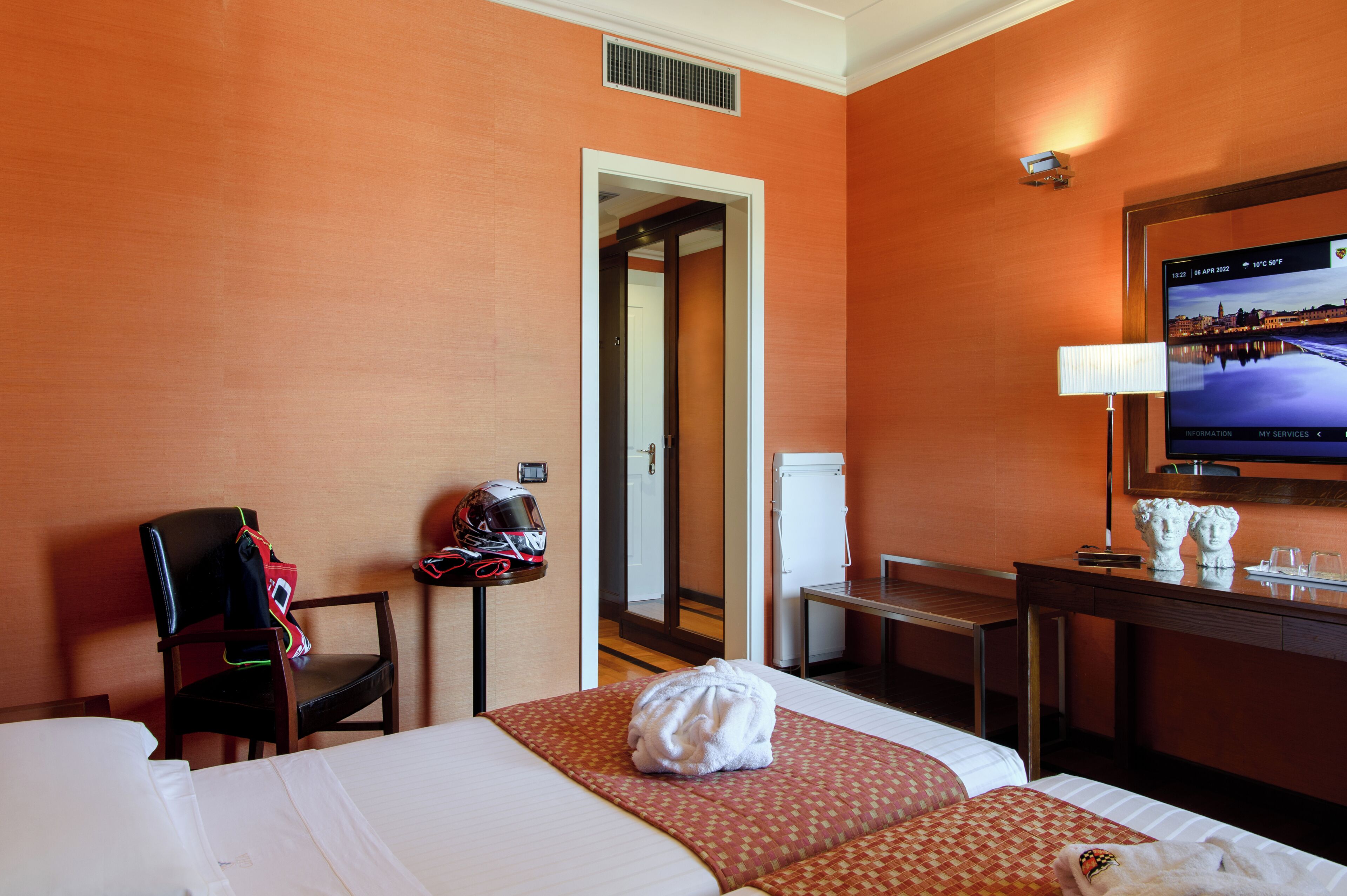 A hotel room with a bed, a chair, a desk, a television, and a mirror.