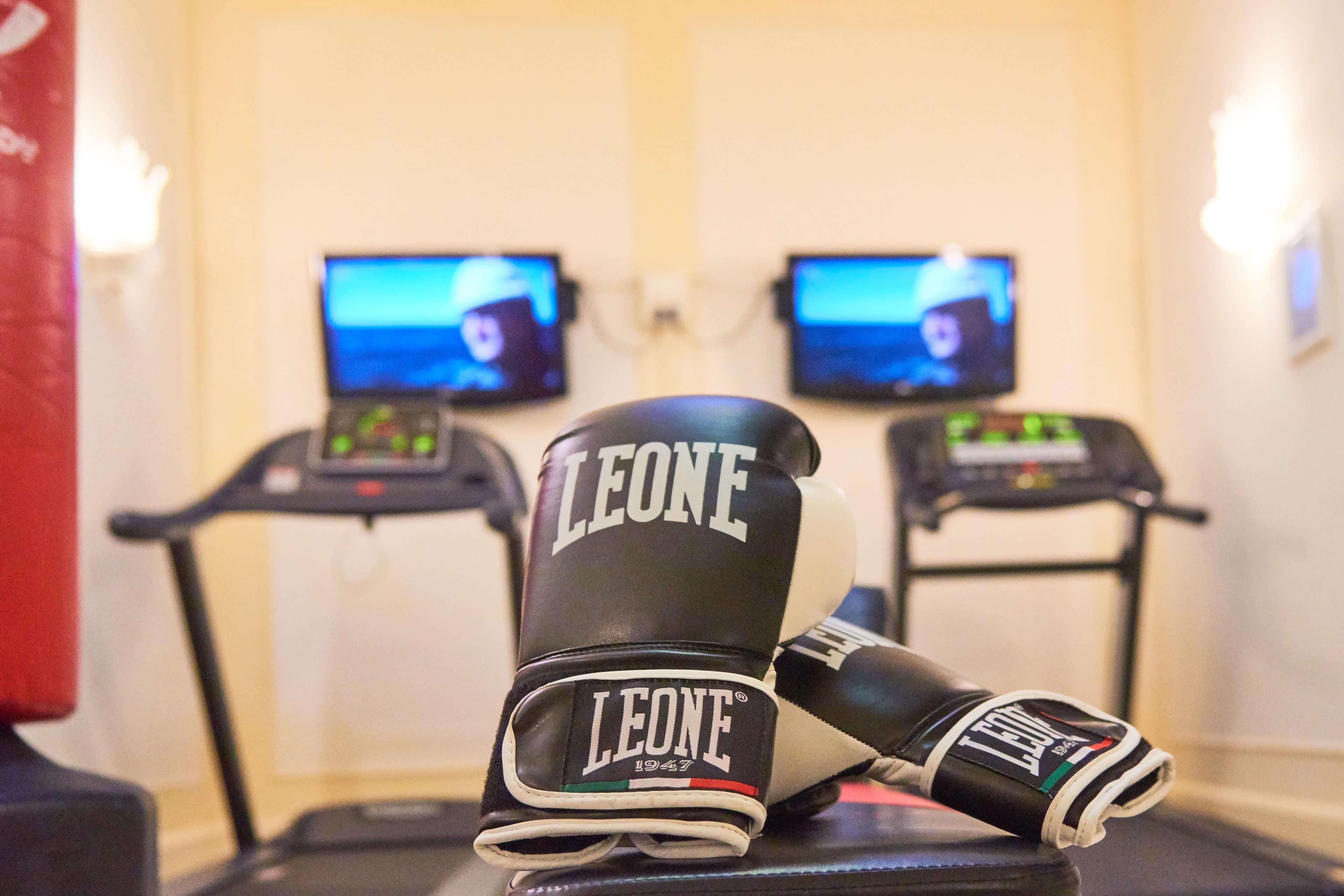 A pair of boxing gloves on a bench with treadmills in the background.