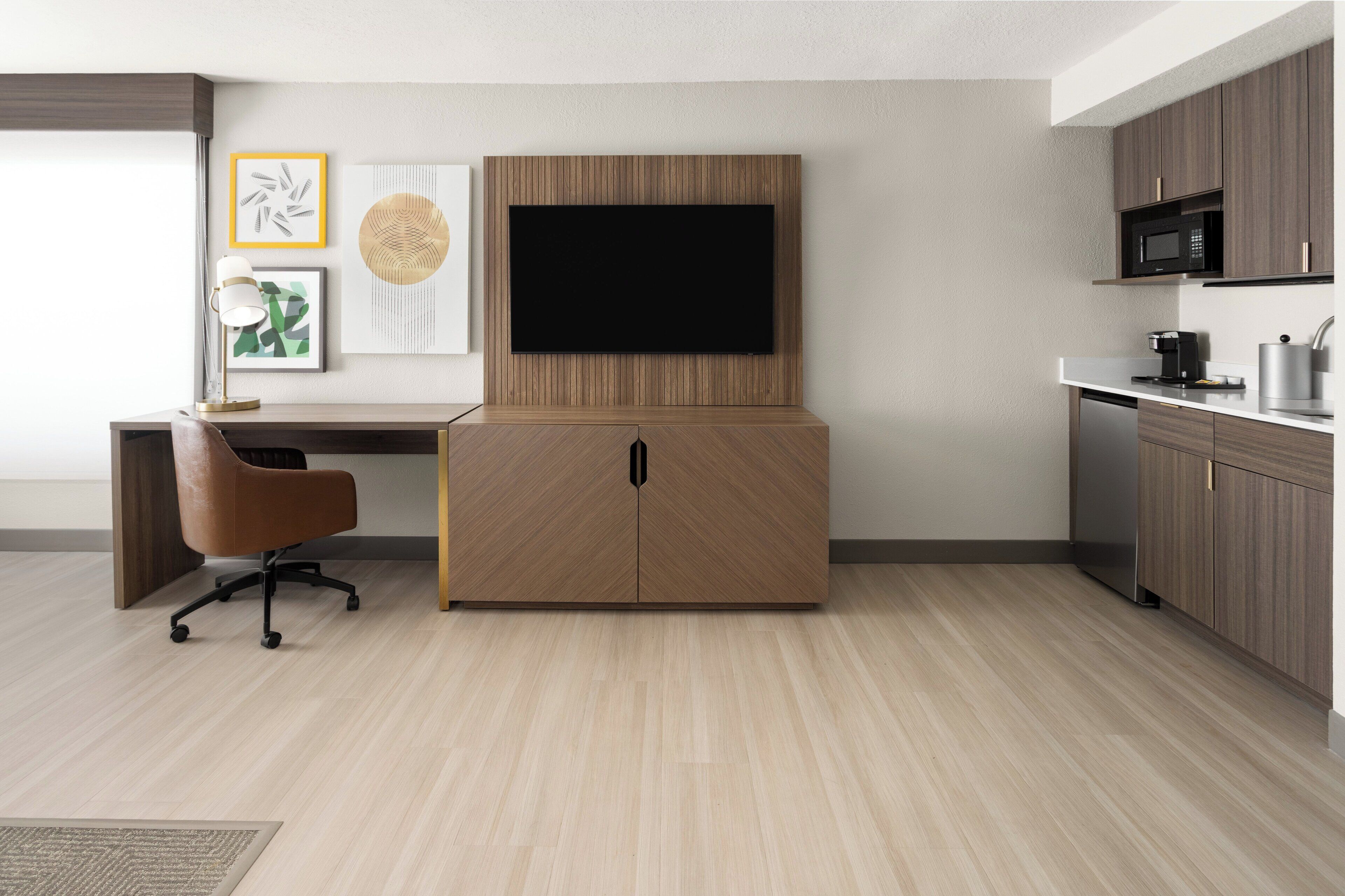 A modern kitchen with a built-in TV, wooden cabinets, and a coffee maker.