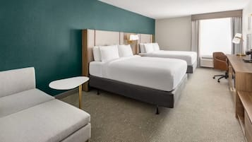 Una habitación de hotel con dos camas, un sofá, un escritorio y una mesita.