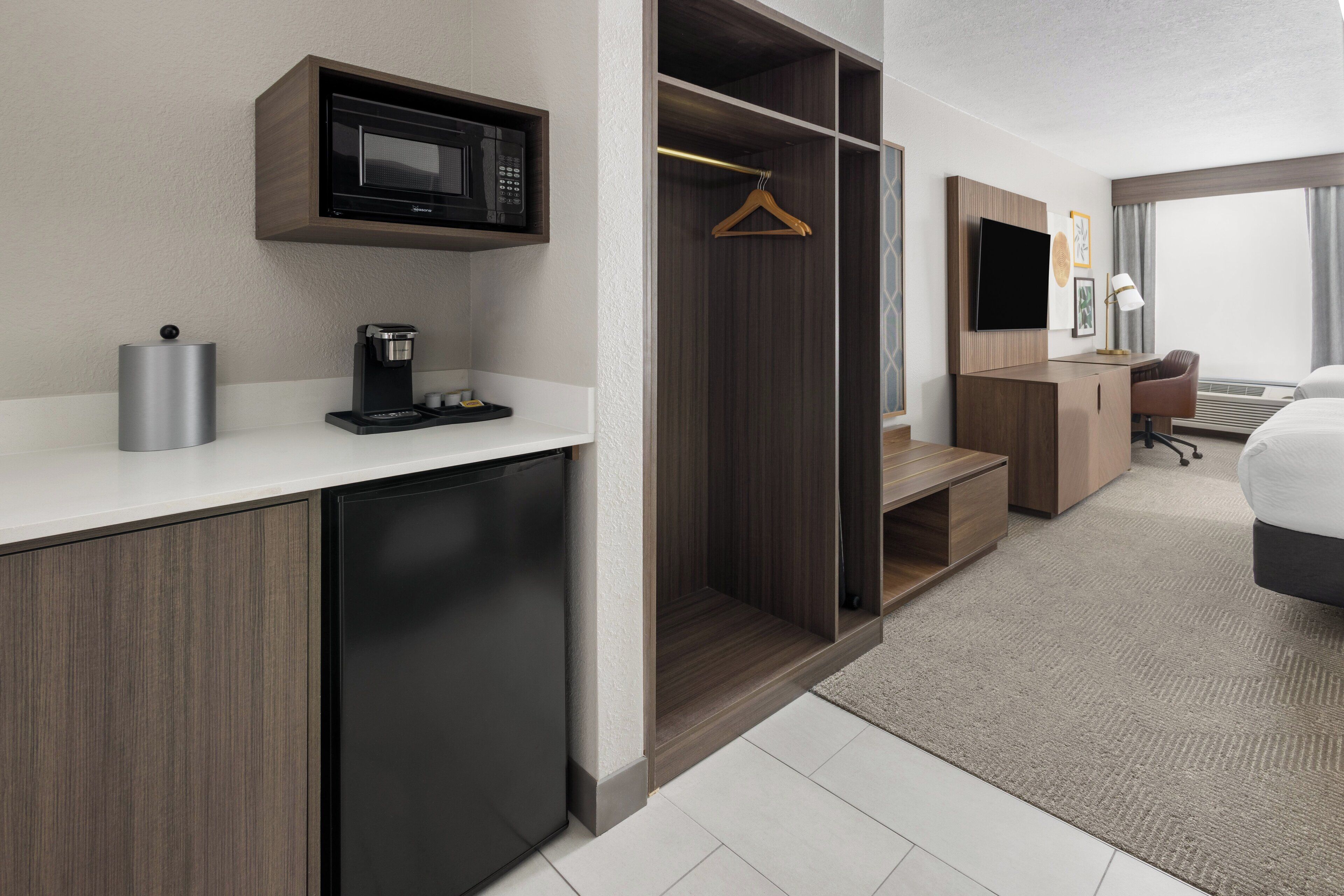 Quarto de hotel com cozinha compacta, cama, escrivaninha e closet espaçoso.