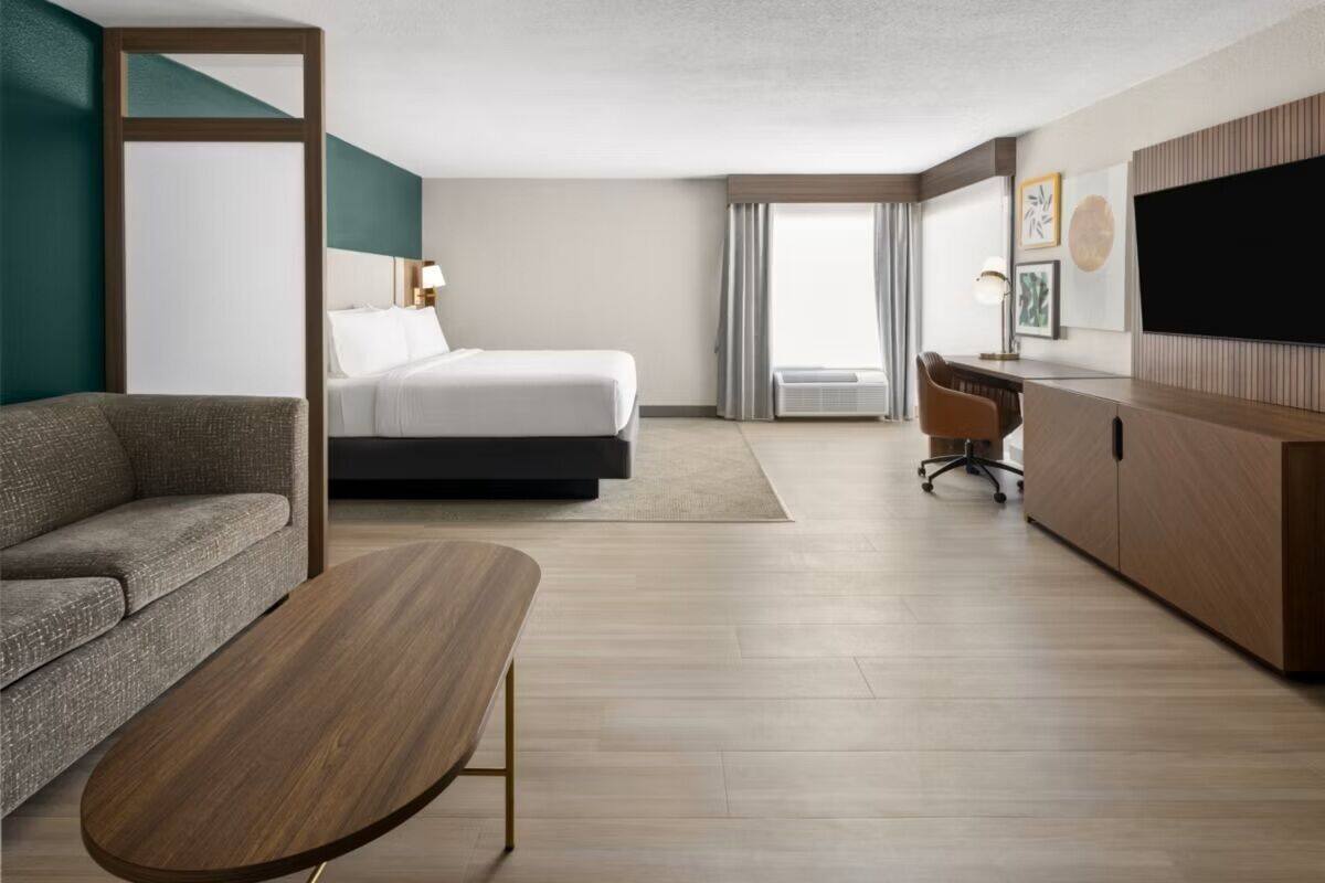 A hotel room with a bed, a sofa, a desk, and a TV.