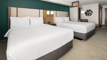 Una habitación de hotel con dos camas, un cabecero de madera, una lámpara de pared y suelo alfombrado.