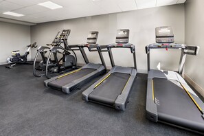 Una palestra con tapis roulant, cyclette e vogatore.