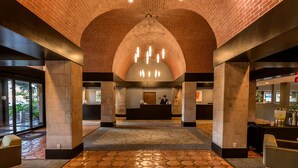 A lobby with a brick ceiling, a reception desk, and a patterned floor. - DoubleTree Suites by Hilton Hotel McAllen (McAllen)