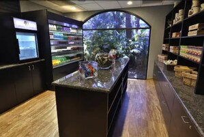 Un área de bar moderna con un acuario grande, estantes llenos de bebidas y piso de madera.