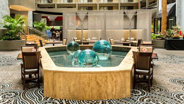 A hotel lobby with a central hot tub, seating area, and a view of the upper floors. - DoubleTree Suites by Hilton Hotel McAllen (McAllen)