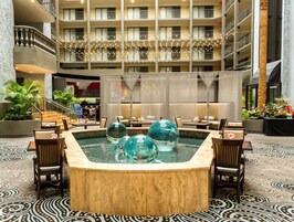 Un vestíbulo de hotel con un jacuzzi central, zona de estar y vistas a los pisos superiores.