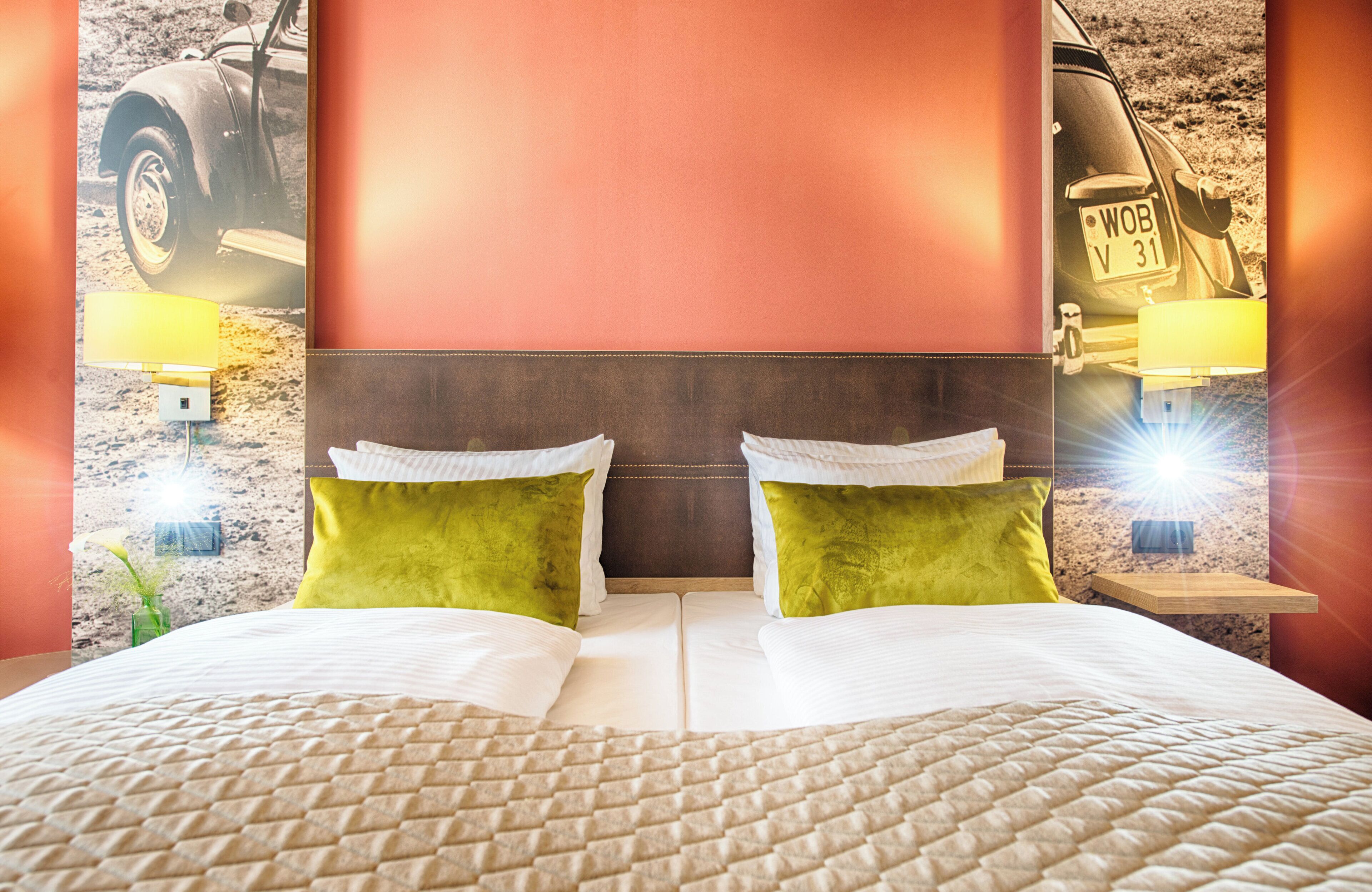 A double bed with green pillows, a headboard, and two bedside lamps.