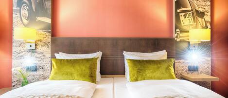 A double bed with green pillows, a headboard, and two bedside lamps.