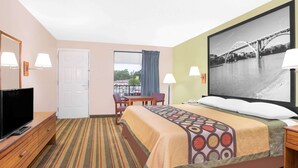 Une chambre d’hôtel comprenant un lit, une télévision, un bureau, une chaise, une fenêtre donnant sur un pont et une porte.