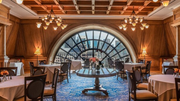 A dining area with round tables, chairs, and chandeliers. - Hotel Crescent Court (Dallas)