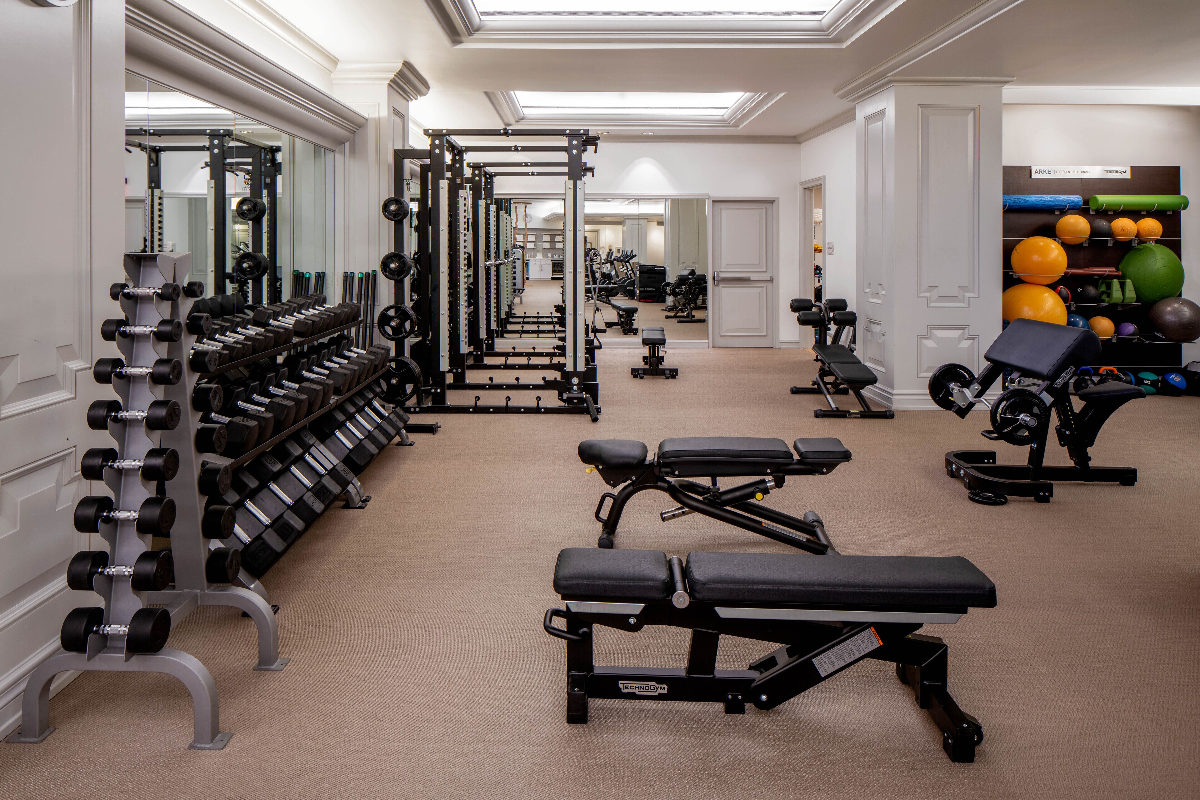A gym with weightlifting equipment, benches, and exercise balls.