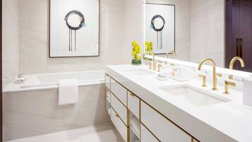 A modern bathroom with a white vanity, gold faucets, and a large mirror.