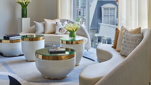 A modern living room with a sofa, two side tables, and a large window with a city view. - Hotel Crescent Court (Dallas)
