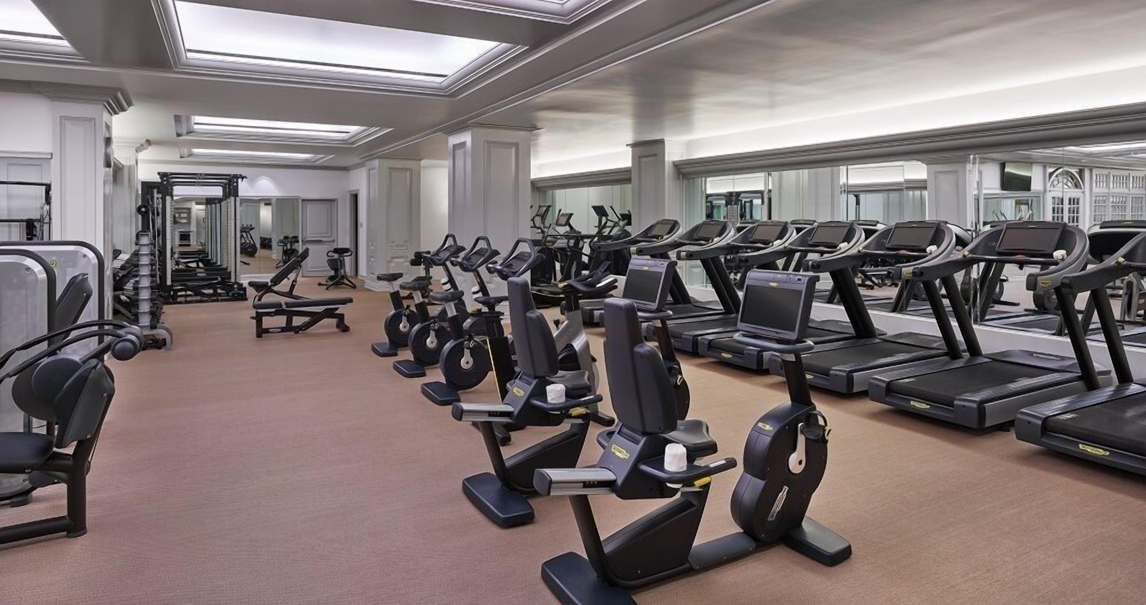 Une salle de sport équipée de plusieurs tapis de course, de vélos elliptiques et d’appareils de musculation.
